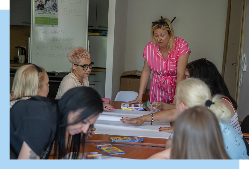 Wielkopolskie Stowarzyszenie Inicjatyw Lokalnych „Zielona Kropka” Zdjęcie przedstawia grupę kobiet, które wspólnie pracują nad projektem. Jedna z nich stoi, pozostałe siedzą. Autorem fotografii jest Maciej Motylewski.