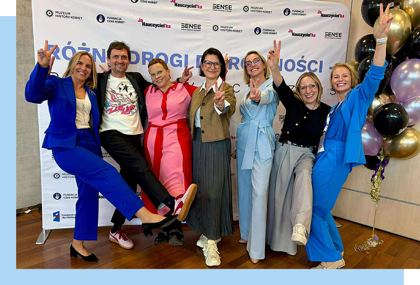 Fotografia przedstawia grupę siedmiu osób, w tym sześć pań i jeden pan, którzy wesoło pozują do zdjęcia.