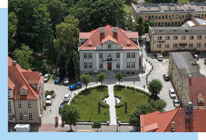 Zdjęcie z lotu ptaka przedstawia elegancki, odnowiony budynek ze spadzistym dachem krytym czerwoną dachówką.